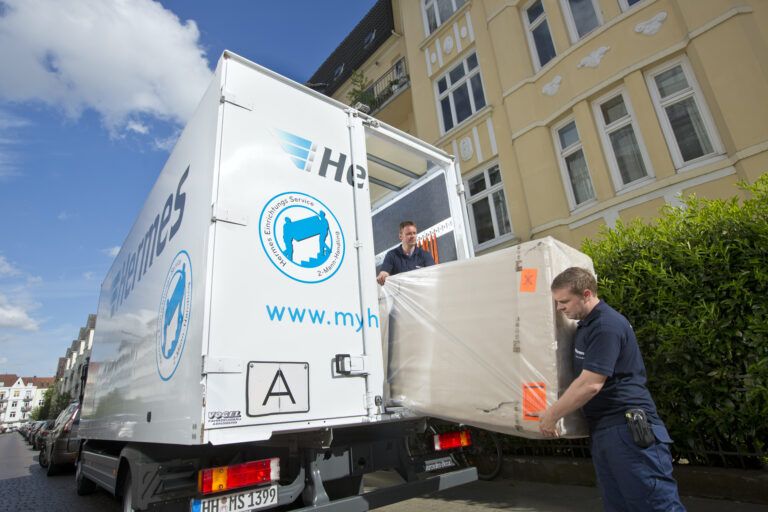 Männer verladen verpacktes Möbelstück in LKW