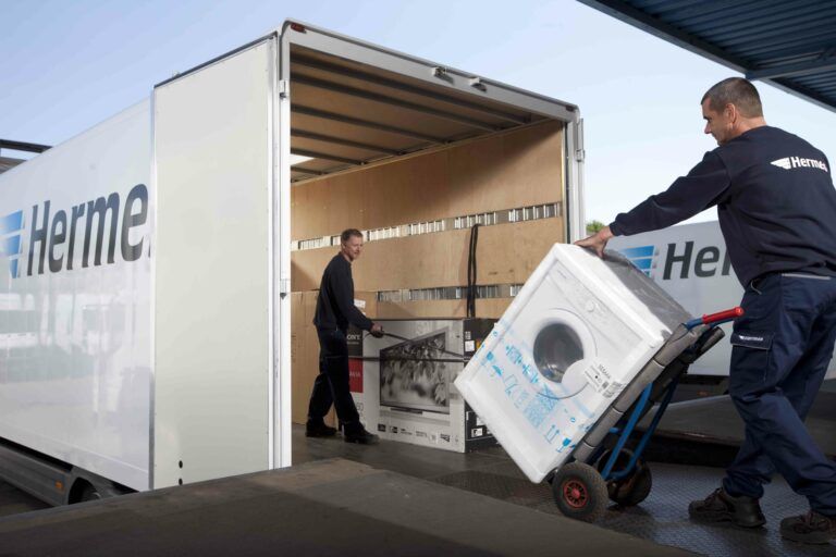 Männer verladen verpackte Waschmaschine in LKW